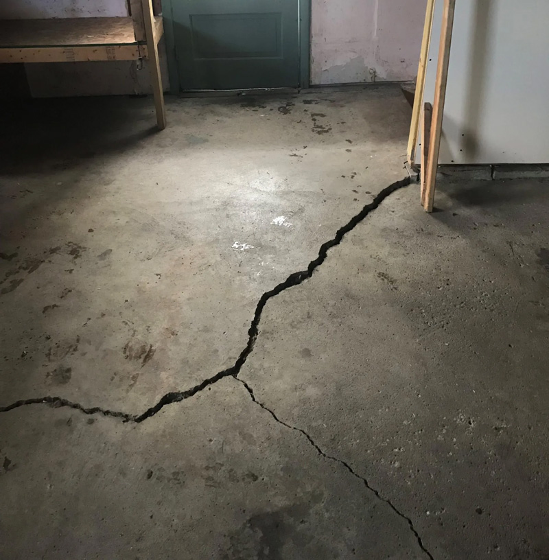 Large structural crack in a concrete floor illustrating a scenario where concrete slab replacement or repair must be evaluated based on crack depth.