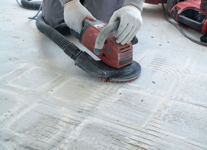Close-up of diamond tooling on a portable grinder removing surface laitance during concrete floor preparation.