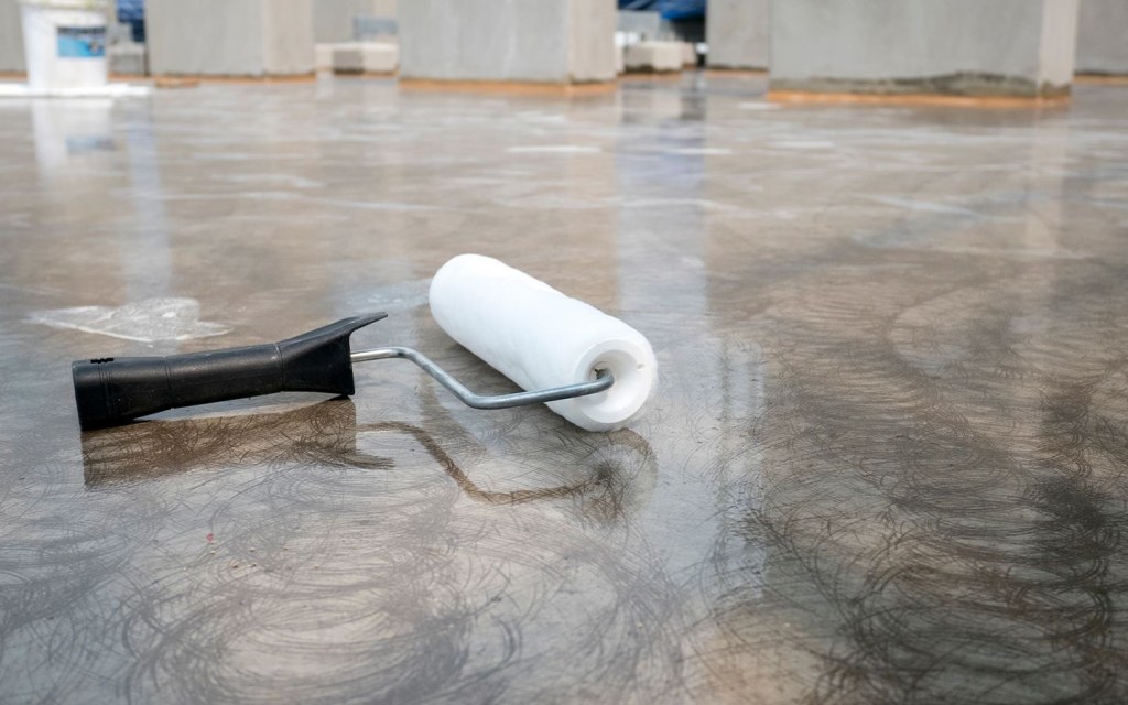 Applying thin epoxy paint with a roller versus a professional high-build epoxy coat for long-term concrete protection.