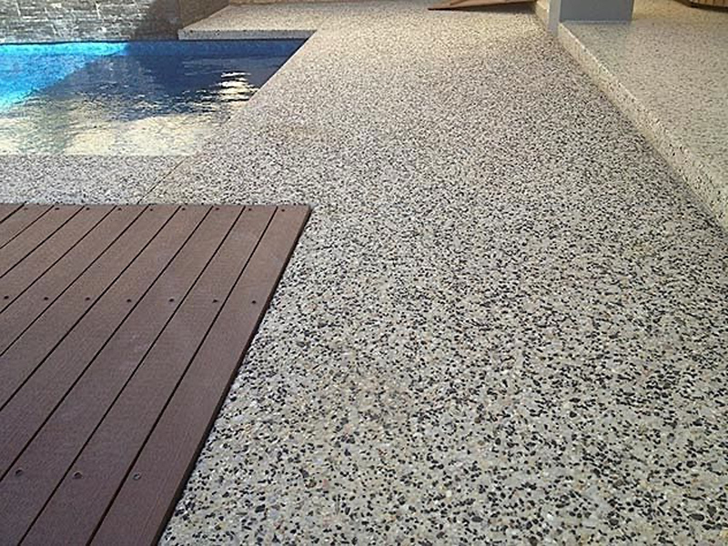 Non-slip pebbled polished concrete outdoor area surrounding a swimming pool.